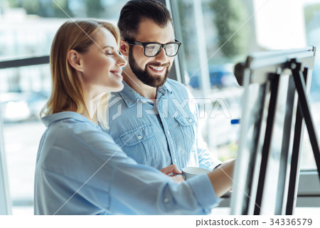 Cheerful colleagues writing on whiteboard in 34336579