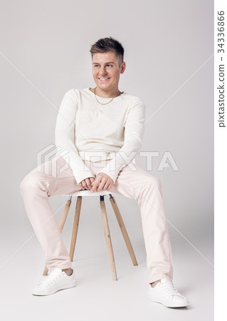 handsome young man in white sweater sits on a 34336866