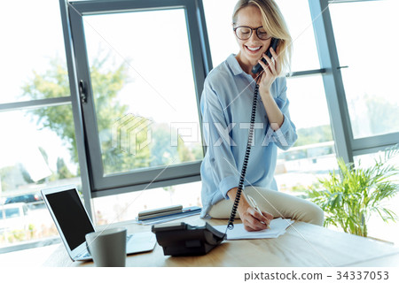 Pleasant woman talking on phone and putting down Pleasant woman talking on phone and putting down 34337053