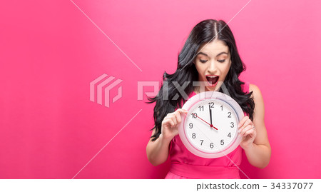 Woman holding clock showing nearly 12 Woman holding clock showing nearly 12 34337077