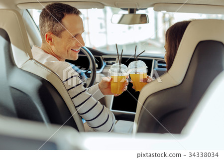 Joyful positive couple cheering with juice Joyful positive couple cheering with juice 34338034