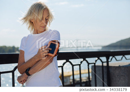 Charming elderly woman using phone in arm band 34338179