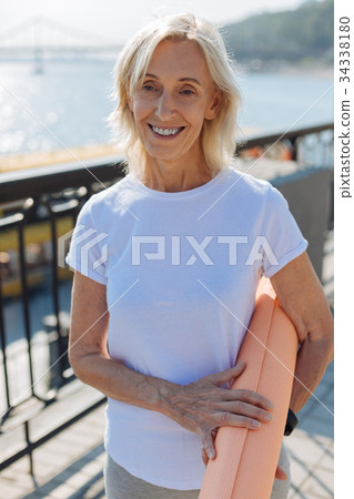 Upbeat senior woman posing with a yoga mat on Upbeat senior woman posing with a yoga mat on 34338180