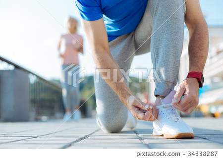 Close up of sporty senior man tying shoelaces on 34338287