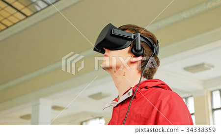 Young man in VR headset playing virtual game 34338359