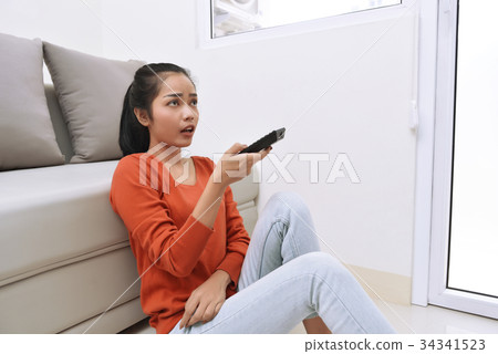 Asian woman watching television while sitting 34341523