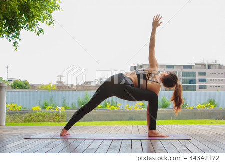 young women doing yoga pose at the park young women doing yoga pose at the park 34342172