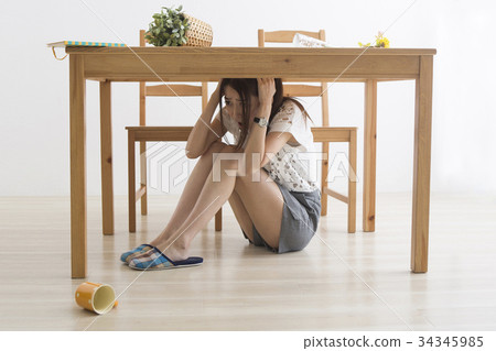 Woman evacuating under the table by earthquake 34345985