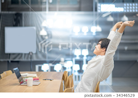 Young Asian man stretching out arm in workspace Young Asian man stretching out arm in workspace 34346529