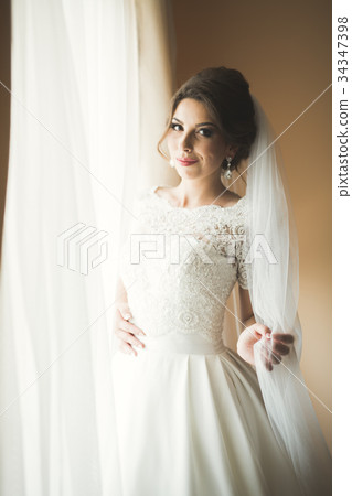 Luxury bride in white dress posing while preparing Luxury bride in white dress posing while preparing 34347398