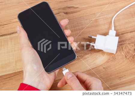 Hand connects plug of charger mobile phone Hand connects plug of charger mobile phone 34347473