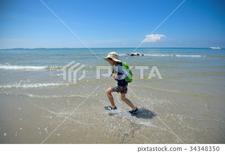 The boy runs to the sea at the beach cheerfully cheerful. On a c 34348350