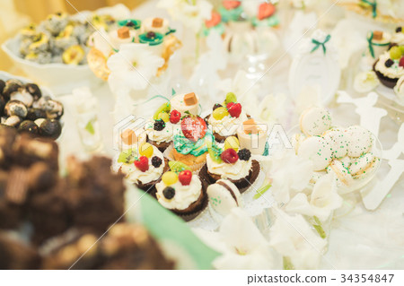 Delicious and tasty dessert table with cupcakes Delicious and tasty dessert table with cupcakes 34354847