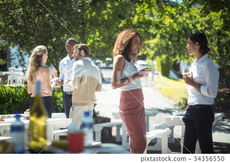 Friends interacting while having glass of wine in restaurant 34356550