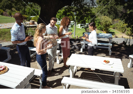 Friends interacting while waitress serving food 34356595