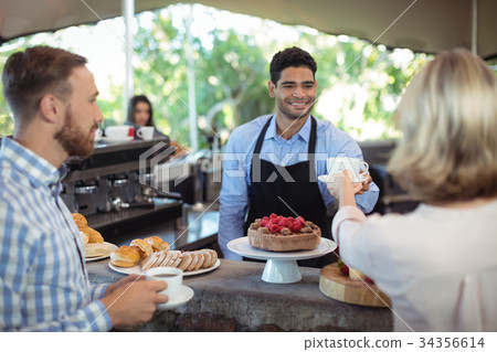 Waiter serving coffee to customer at counter 34356614