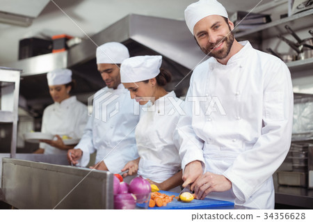Chefs chopping vegetables on chopping board in the commercial kitchen 34356628