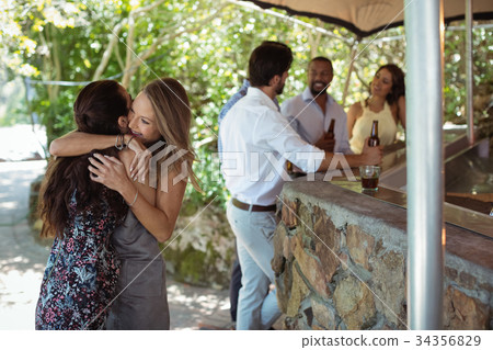Friends embracing each other at counter Friends embracing each other at counter 34356829
