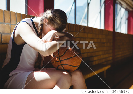 Tired basketball player sitting by window Tired basketball player sitting by window 34356982