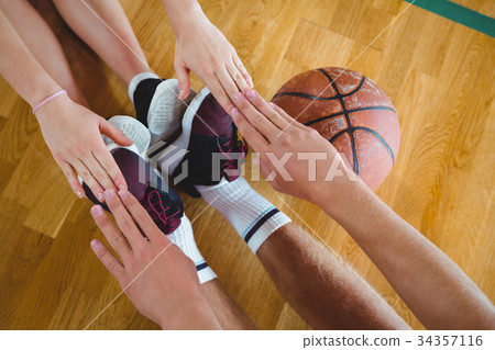 Friends exercising while sitting on hardwood floor in court Friends exercising while sitting on hardwood floor in court 34357116