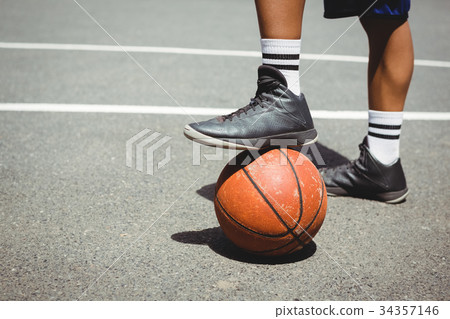 Low section of man standing with one leg on basketball 34357146