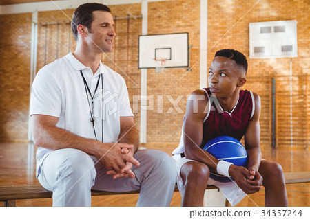 Smiling coach guiding basketball player Smiling coach guiding basketball player 34357244