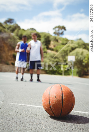 Basketball on ground with player standing in background 34357266