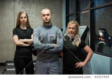 Portrait of friends standing against treadmills Portrait of friends standing against treadmills 34357455