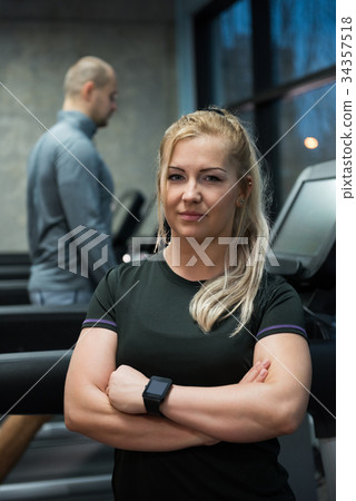 Portrait of woman standing with man exercising on treadmill Portrait of woman standing with man exercising on treadmill 34357518