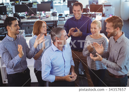 Happy businessman standing by colleagues clapping 34357657