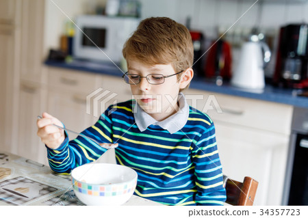 Happy little blond kid boy eating cereals for 34357723