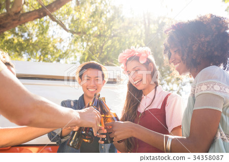 Smiling friends toasting beer bottles Smiling friends toasting beer bottles 34358087