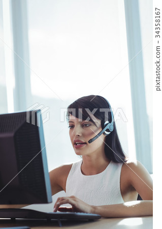 Businesswoman talking on headset while working at call center 34358167