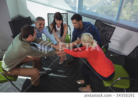 High angle view of business colleagues stacking hands at office 34358191