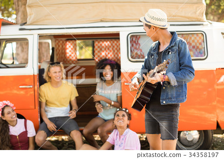 Friends looking at man playing guitar Friends looking at man playing guitar 34358197