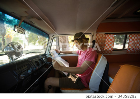 Side view of man reading map in camper van 34358282
