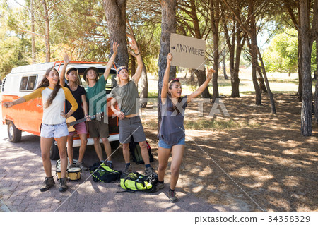 Happy friends hitchhiking on road Happy friends hitchhiking on road 34358329