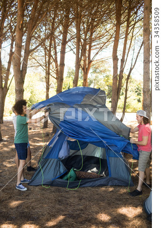 Full length of friends making tent Full length of friends making tent 34358509