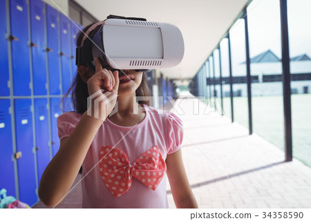 Elementary student using virtual reality glasses in corridor Elementary student using virtual reality glasses in corridor 34358590