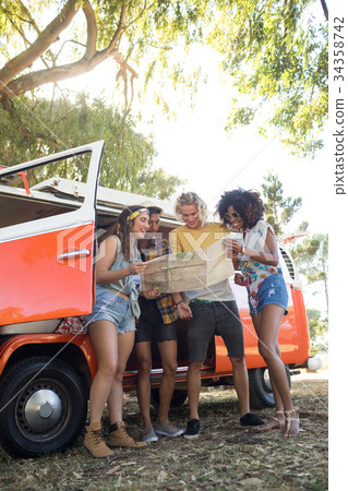 Low angle view of friends looking at map at campsite 34358742