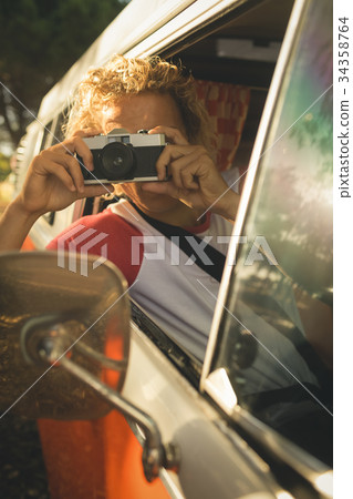 Man photographing through camera while sitting in van 34358764
