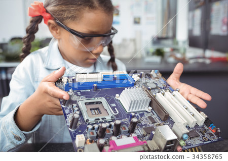 Elementary schoolgirl examining circuit board at electronics lab 34358765