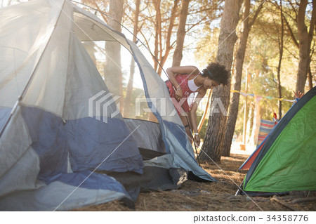 Young woman setting up tent on field Young woman setting up tent on field 34358776