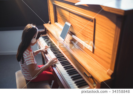 High angle view of concentrated girl practicing piano 34358848
