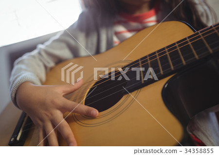 Mid section of girl practicing guitar 34358855