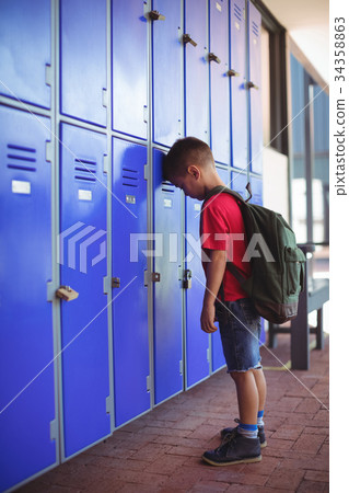 Side view of boy leaning on lockers in corridor Side view of boy leaning on lockers in corridor 34358863