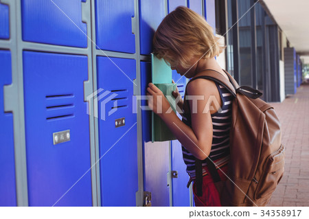 Sad boy leaning on lockers in corridor 34358917