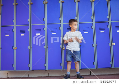 Boy looking away while using mobile phone against lockers 34358971