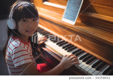 High angle portrait of girl wearing headphones while practicing piano 34359052