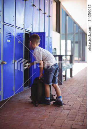 Full elngth of boy taking books from locker 34359085